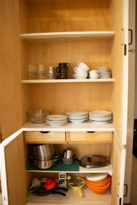 une armoire remplie de assiettes, de bols et de vaisselle dans l'établissement Villa Isolda: moderno trilocale, à Bibione