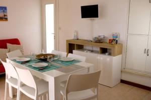 comedor con mesa blanca y sillas blancas en Villa Isolda: moderno trilocale, en Bibione