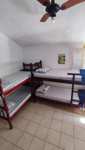two bunk beds in a room with a ceiling fan at Maré Alta Hostel in Ubatuba