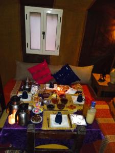 - une table avec de la nourriture et des boissons au-dessus d'un lit dans l'établissement Merzouga Luxury Desert camp, excursion and activities, à Merzouga
