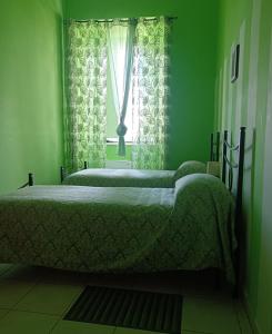 two beds in a green room with a window at Casa Tabor in Ariano Irpino
