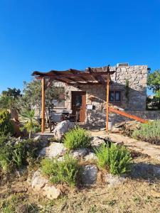 une petite maison en pierre avec une pergola en bois dans l'établissement Ηλιοβασίλεμα, à Chios