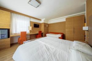 - une chambre avec un grand lit blanc et un bureau dans l'établissement Barisetti Sport Hotel, à Cortina dʼAmpezzo