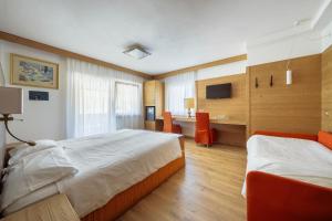 um quarto de hotel com duas camas e uma secretária em Barisetti Sport Hotel em Cortina dʼAmpezzo