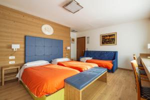 una camera con due letti e un orologio a muro di Barisetti Sport Hotel a Cortina dʼAmpezzo