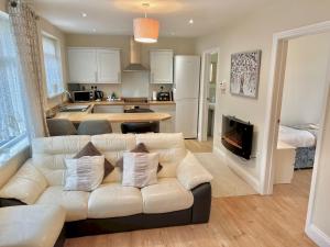 a living room with a white couch and a kitchen at Modern Cosy home Limeslade Bay Pass the Keys in The Mumbles