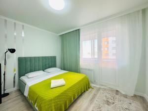 een slaapkamer met een bed met een gele deken bij Sezim Qala in Astana