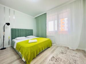 een slaapkamer met een bed met een gele deken bij Sezim Qala in Astana