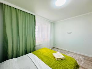 een slaapkamer met een groen gordijn en een bed met 2 handdoeken bij Sezim Qala in Astana