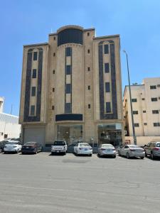 ein großes Gebäude mit Autos auf einem Parkplatz in der Unterkunft فيو بلس للشقق الفندقية in Chamis Muschait