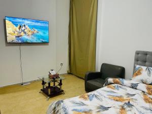 a living room with a couch and a tv on the wall at Relaxation Quiet Room Apartment in Abu Dhabi