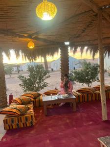 una mujer sentada en una mesa bajo una tienda en Merzouga Luxury Desert camp, excursion and activities en Merzouga