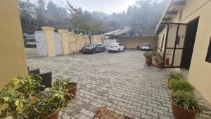 a parking lot with parked cars and potted plants at Shelton Hotel & Restaurant in Sarai