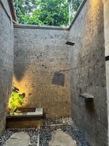 a shower in a concrete wall with a window at The Alus Cottage and Villa in Ubud