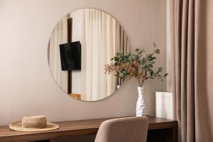 a mirror on a wall above a table with a chair at Hotel Naiades in Órma