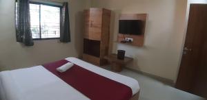 um pequeno quarto com uma cama e uma janela em Hotel The Grand em Mahabaleshwar