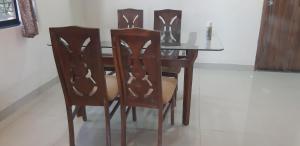 uma mesa de jantar com 4 cadeiras e uma mesa de vidro em Hotel The Grand em Mahabaleshwar
