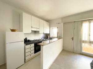 una cucina con armadietti bianchi e frigorifero bianco di Nuovo Appartamento Ristrutturato in Corte Interna a La Maddalena