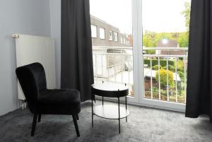 a room with a chair and a table and a window at Hotel Deluxe in Dorsten