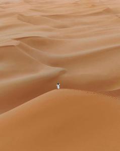 een man op een zandduin in de woestijn bij Merzouga Luxury Desert camp, excursion and activities in Merzouga