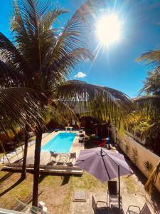 een zwembad met een palmboom en een parasol bij Residencial Costa Mar in Rio das Ostras