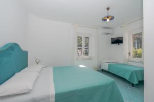 ein weißes Schlafzimmer mit einem Bett und einem Fenster in der Unterkunft Little House in Minori