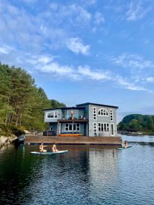a house on a dock with people on surfboards in the water at Floating Villa Bergen in Bergen