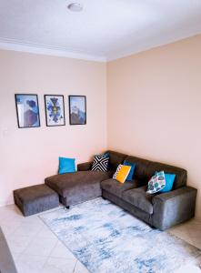 uma sala de estar com um sofá castanho com almofadas coloridas em GEORGE’S PLACE em Kira