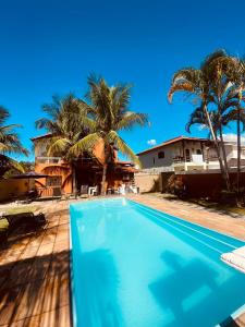 una piscina di fronte a una casa con palme di Residencial Costa Mar a Rio das Ostras