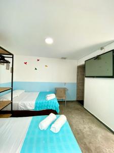 a bedroom with two beds and a flat screen tv at Hotel Anauco in Bucaramanga