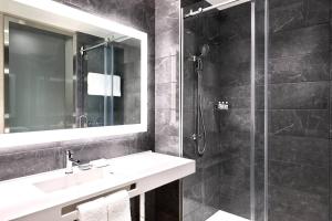 a bathroom with a sink and a shower with a mirror at AC Hotel by Marriott Charlotte SouthPark in Charlotte