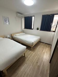 2 camas en una habitación con cortinas azules en GEGE house 201室, en Osaka