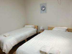 2 camas en una habitación con sábanas blancas en GEGE house 201室, en Osaka
