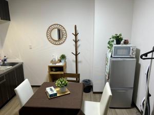 a small kitchen with a table and a microwave on a refrigerator at GEGE house 201室 in Osaka +10 photos