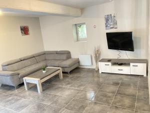 a living room with a couch and a flat screen tv at A&J Family - Neuvy sur Loire - Guédelon in Neuvy-sur-Loire