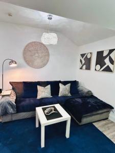 uma sala de estar com um sofá azul e uma mesa em HOME Hertford em Hertford