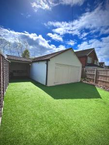 a backyard with a white garage and green grass at HOME Hertford in Hertford