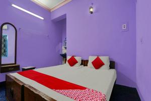 een slaapkamer met paarse muren en een bed met rode kussens bij OYO Sri Sivasakthi A/C Lodge in Sivakāsi