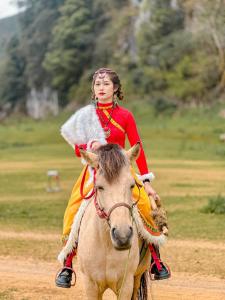 a woman riding on a horse in a field at Homestay Yến Long in Lạng Sơn