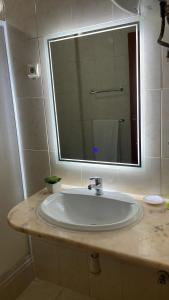 a bathroom sink with a large mirror above it at Felicidade Hotel in Praia