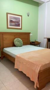 1 dormitorio con 1 cama grande y cabecero de madera en Felicidade Hotel, en Praia