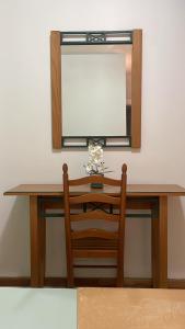a dressing table with a mirror and a wooden chair at Felicidade Hotel in Praia