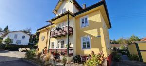 a yellow house with a balcony on a street at Ferienwohnung Oase in Peißenberg