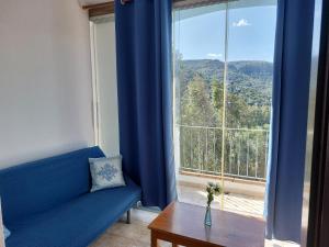 a blue couch sitting in front of a large window at Hotel Valle del Cedrino in Galtellì