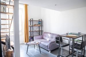 ein Wohnzimmer mit einem Sofa und einem Tisch in der Unterkunft PETIT DUPLEX - Nouveau duplex central avec wifi et clim pour 2 in Antibes