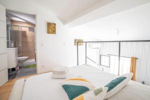 ein weißes Schlafzimmer mit einem Bett und einem Badezimmer in der Unterkunft PETIT DUPLEX - Nouveau duplex central avec wifi et clim pour 2 in Antibes