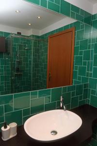 a green tiled bathroom with a sink and a mirror at BellaIseo Luxury rooftop in Pilzone