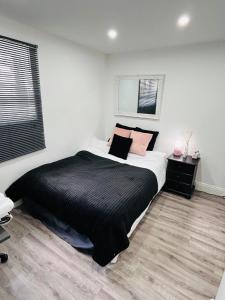 um quarto com uma cama com lençóis pretos e almofadas cor-de-rosa em HOME Hertford em Hertford