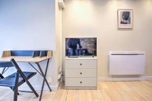 a room with a desk and a tv and a dresser at L'auberge rit ! in Périgueux