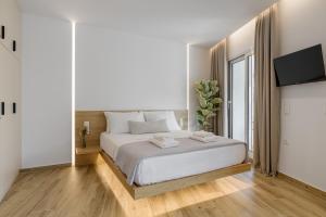 a white bedroom with a white bed and a flat screen tv at Central Sunny Loft with Plunge Pool in Athens
